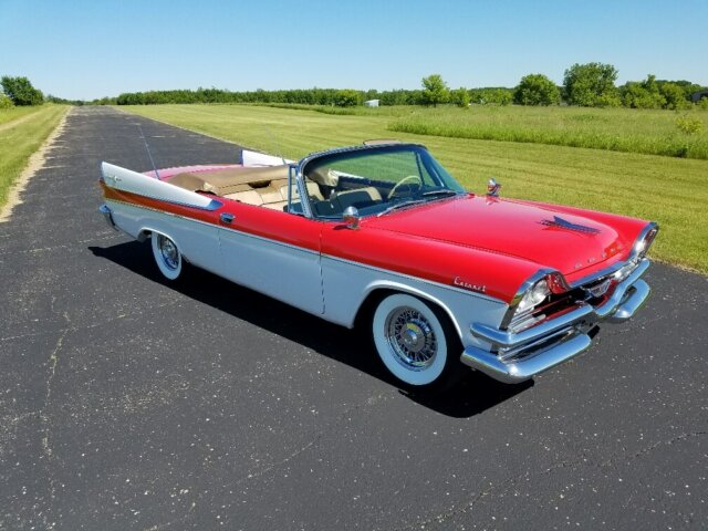 Buy your dream car in the USA picture of a 1957 Dodge Coronet convertible parked on an asphalt road with greenery in the background