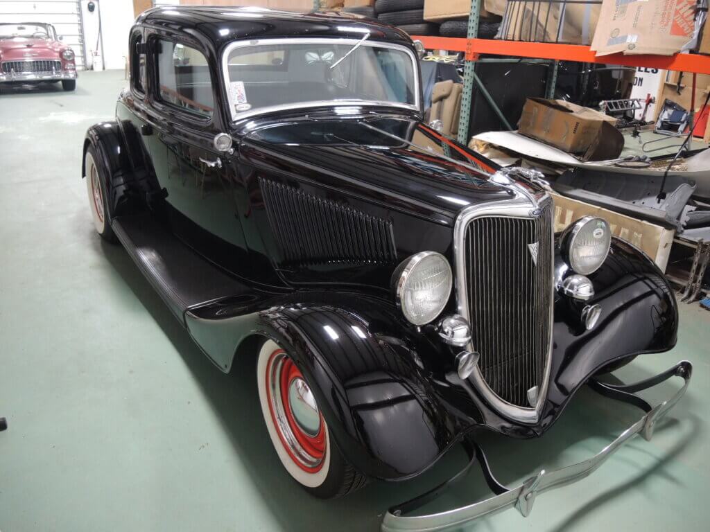 Import car from USA and Canada picture of a black 1934 Ford Coupe hot rod sitting in a garage