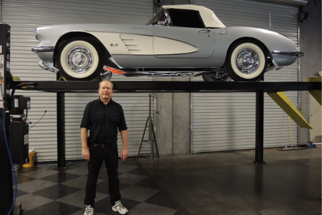 An inspector in front of an American dream car on a lift after a thourough inspection.