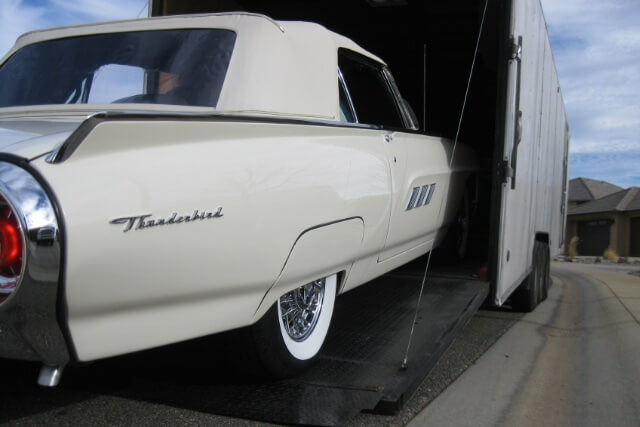 A white American dream car being loaded on an enclosed trailer to be shipped to Sweden.